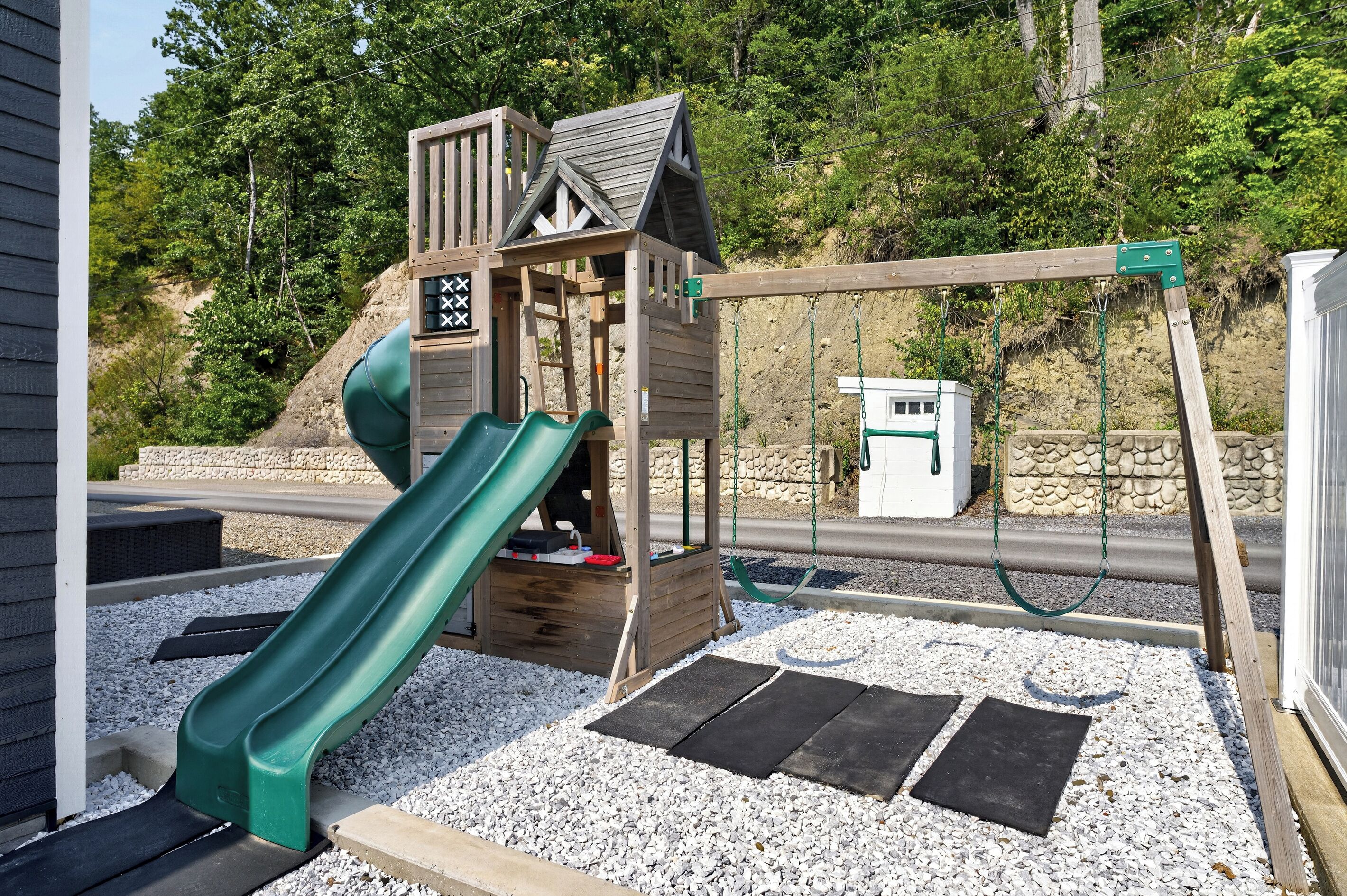 Un parque infantil con un tobogán de madera, columpios y una estructura para escalar.