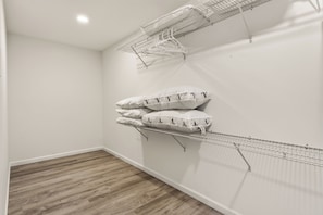 Una habitación con suelo de madera, paredes blancas y estanterías metálicas para tender ropa.