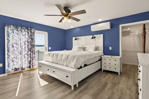 Ein Schlafzimmer mit Bett, Nachttischen, einem Schminktisch, einem Deckenventilator und einem Fenster mit Vorhängen.