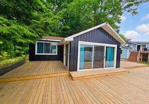 Due cabine moderne con ampie porte scorrevoli in vetro, terrazze in legno e immerse nel verde.