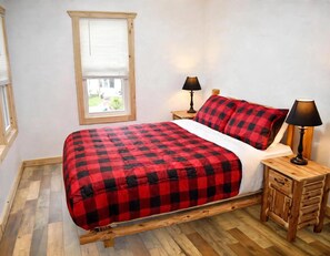 Una camera da letto con un letto, due comodini, una finestra e vista sull'esterno.
