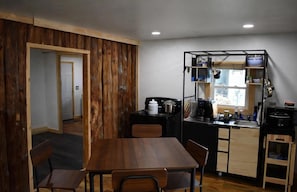 A compact kitchen with a dining area, wooden accents, and a view through a window.