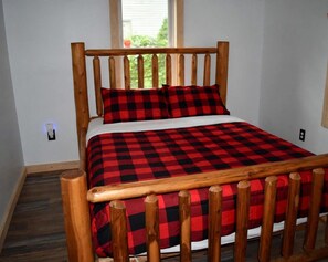 A bed with a wooden frame and a red and black checkered bedspread.