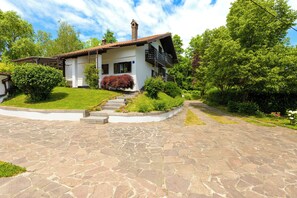 A two-story house with a stone-paved driveway leading to a set of stairs.