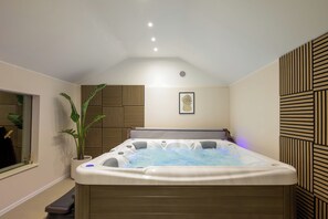 Une salle de bain moderne avec un jacuzzi, une plante en pot et une œuvre d’art encadrée au mur.