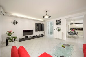 Una sala de estar moderna con televisor de pantalla plana, una mesa de centro de vidrio y sofás rojos.