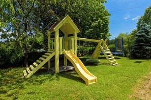 Une aire de jeux avec un toboggan jaune et une structure d’escalade.