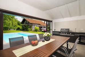 A modern outdoor kitchen with a pool view, a dining table with chairs, and a grill. - Villa Bella Cerovlje (Istria - Cerovlje) (Cerovlje)