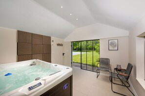 A spa room with a hot tub, a view of a garden, and a seating area with chairs. - Villa Bella Cerovlje (Istria - Cerovlje) (Cerovlje)