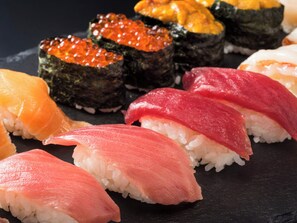 A variety of sushi on a black slate plate.