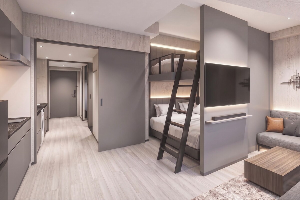 A modern interior with a bunk bed, a flat-screen TV, a sofa, and a kitchen area.