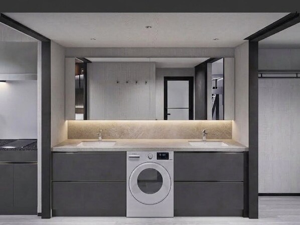 A modern bathroom with a double sink, a built-in washing machine, and a large mirror.