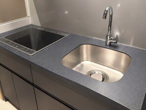 A modern kitchen with a built-in induction cooktop and a stainless steel sink.