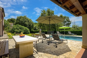 An outdoor patio with a pool, lounge chairs, and a table with fruit. - Villa Morena (Istria - Tinjan) (Tinjan)