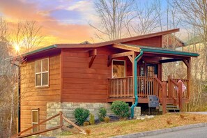 A wooden cabin with a porch, a mailbox, and a small garden. - Moonlight Memories Cabin Rental (Pigeon Forge)