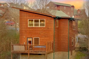 A wooden cabin with a balcony, a window with a view, and a door. - Moonlight Memories Cabin Rental (Pigeon Forge)