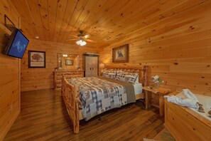 A wooden cabin bedroom with a bed, a nightstand, a dresser, a ceiling fan, and a framed picture on the wall. - Moonlight Memories Cabin Rental (Pigeon Forge)