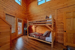 A wooden cabin interior with a bunk bed, a door, and a window. - Moonlight Memories Cabin Rental (Pigeon Forge)