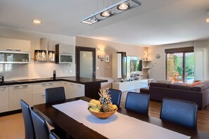 Eine moderne Küche mit Essbereich, ein Wohnzimmer mit Sofa und Blick ins Freie.