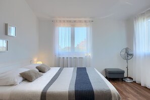 A bedroom with a bed, a bedside table, a standing fan, and a window with curtains. - House Leticia (Istria - Valbandon) (Valbandon)