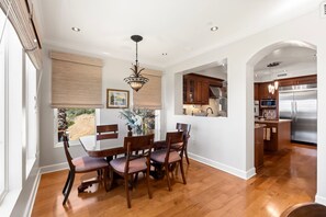 A modern kitchen with stainless steel appliances, wooden cabinets, and a dining area with a table and chairs. - Cozy 3-Suite condo with AC in gorgeous La Jolla, CA.  Owner lives there summers. (San Diego)