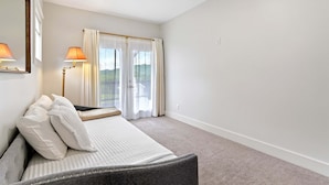 Habitación de hotel con cama, dos lámparas de noche, ventana con cortinas y vistas al exterior.