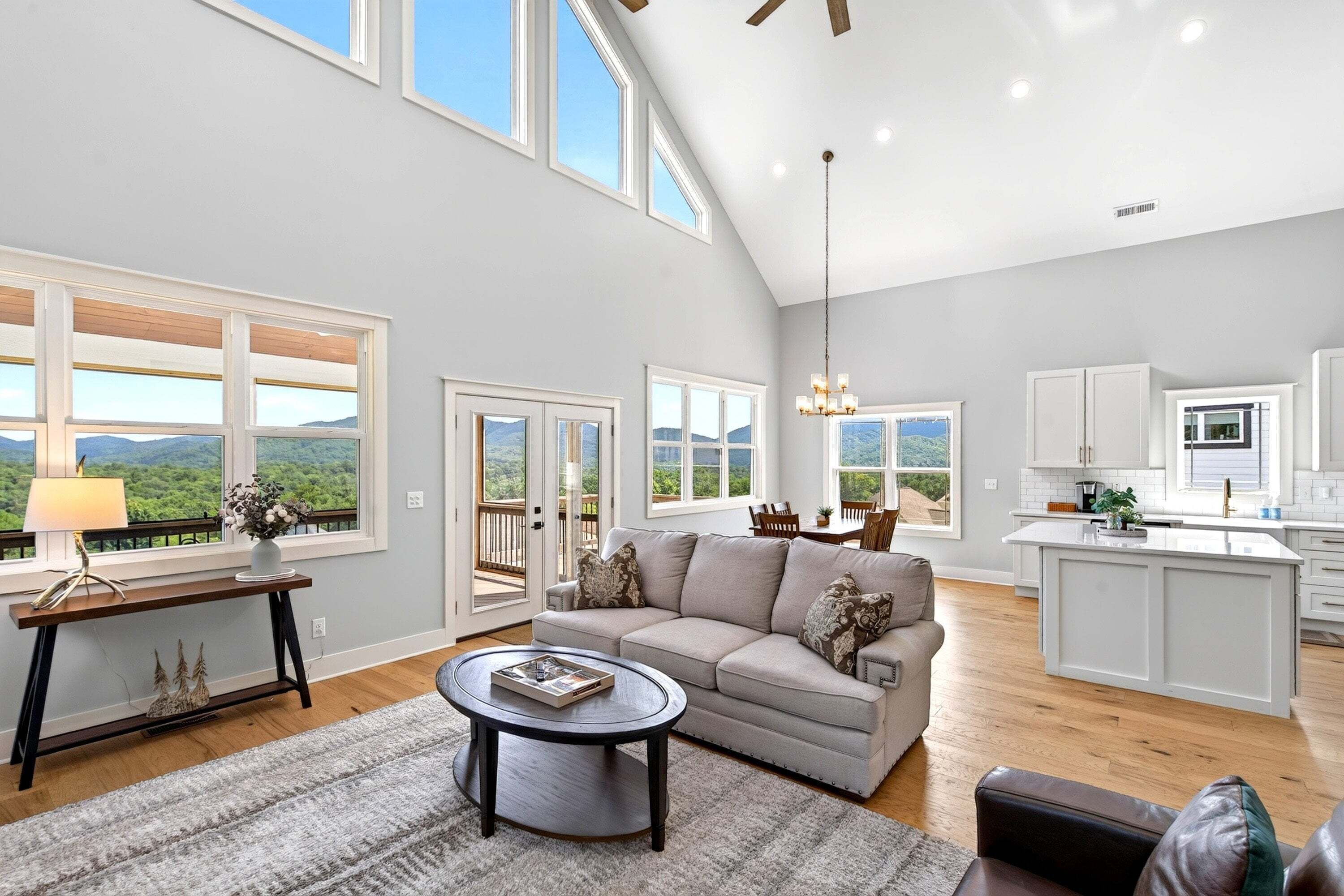 A spacious living room with a large window, a sofa, a coffee table, and a view of the outdoors.