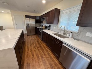 A modern kitchen with dark wooden cabinets, stainless steel appliances, and a marble countertop.