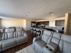 A modern living room with a large L-shaped sofa and a dining area with a kitchen in the background. - Spacious 4-bedroom house in tranquil Clovis with AC (Clovis)