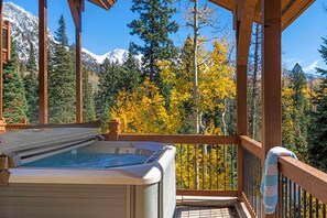 Ein Whirlpool auf einer Holzterrasse mit Blick auf die Berge.