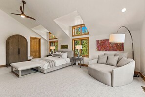 Ein Schlafzimmer mit einem großen Bett, einer Bank, einer Couch und einem Deckenventilator.