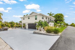A two-story house with a garage, a driveway, and a well-maintained lawn. - NEW! Waterfront 3BR/2BA retreat with king bed, Wi-Fi, grill, and water views. (Saint James City)