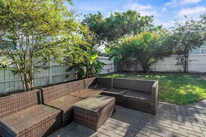 A patio area with wicker furniture, including a sofa and a coffee table. - Blue Palms- Steps away from OCEAN (Galveston)