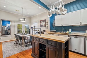 A modern kitchen with a central island, stainless steel appliances, and a blue accent wall. - Blue Palms- Steps away from OCEAN (Galveston)