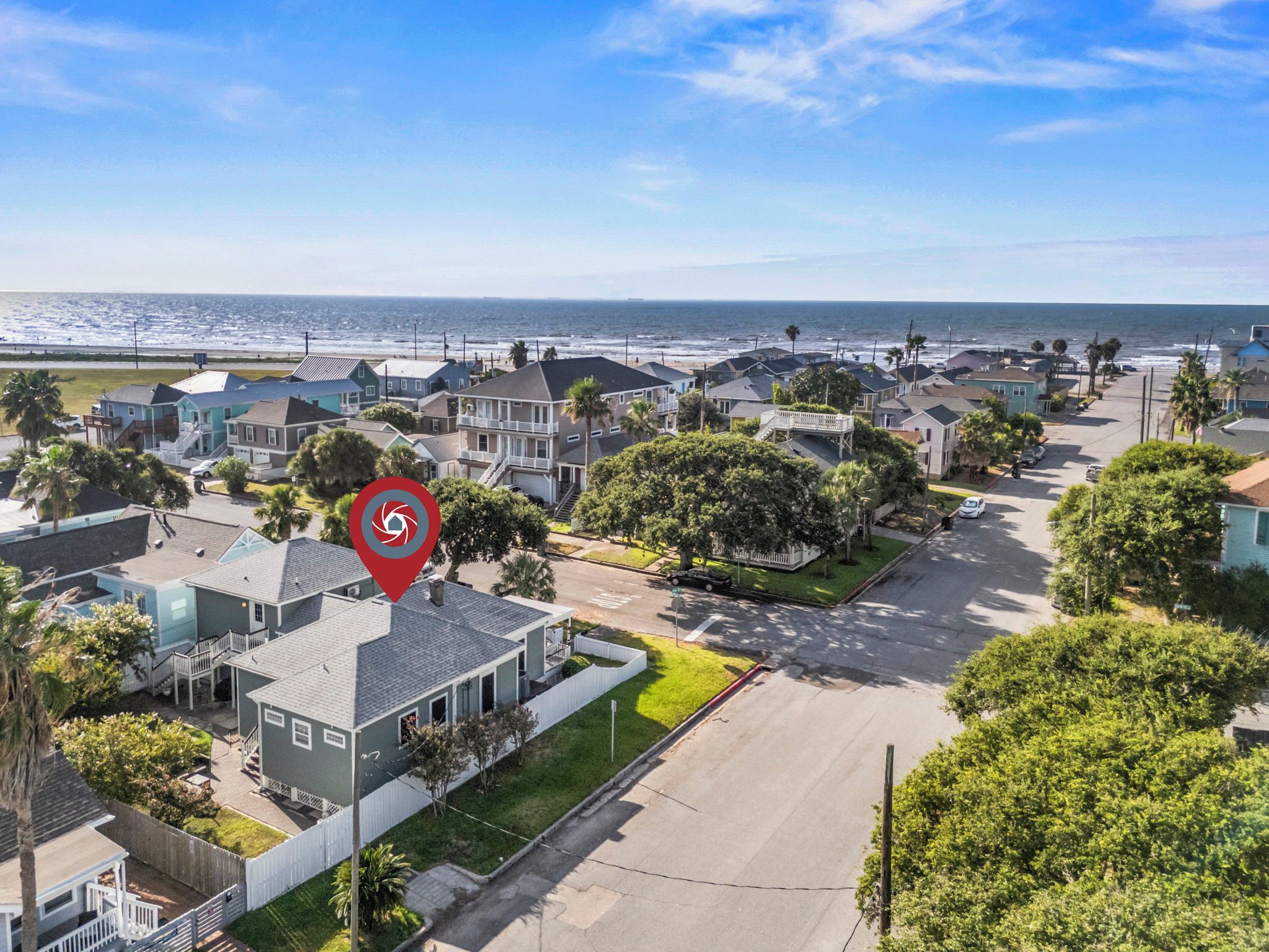 A coastal residential area with houses, a street, and a view of the ocean.