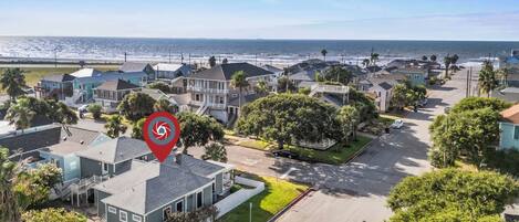 A coastal residential area with houses, a street, and a view of the ocean.