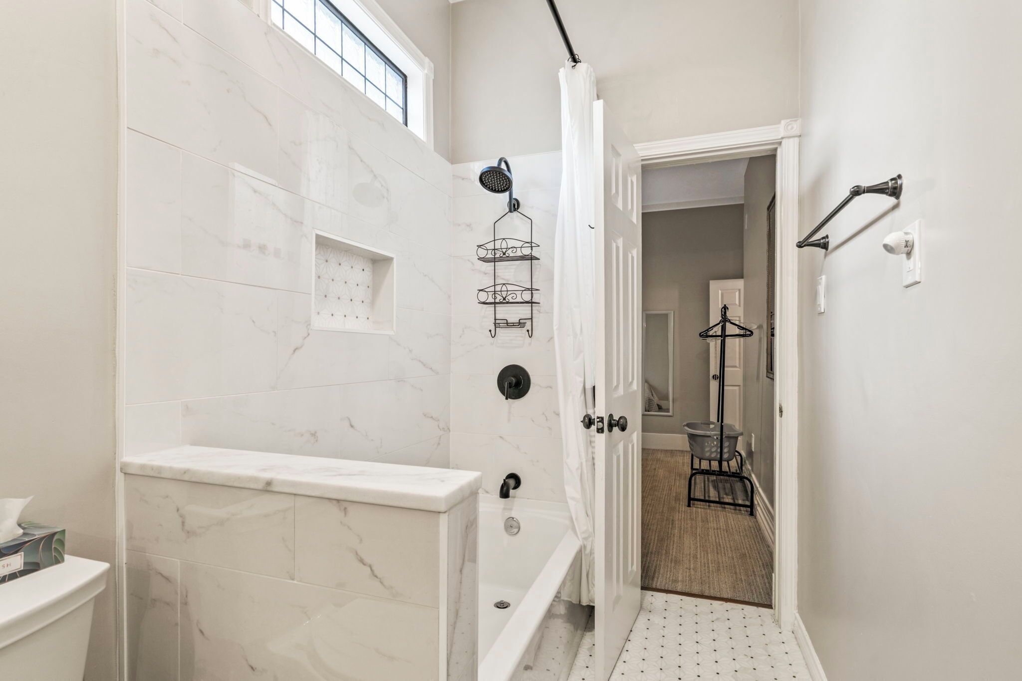 A bathroom with a shower, toilet, and a towel rack.