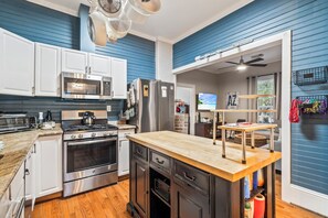 A modern kitchen with stainless steel appliances, a wooden island, and a view to the living area. - Blue Palms- Steps away from OCEAN (Galveston)