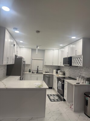 Una cocina moderna con armarios blancos, una isla central y un refrigerador de acero inoxidable.