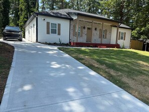 A single-story house with a front porch, a driveway, and a well-maintained lawn. - Spacious 5-Bedroom Home Near Atlanta Airport Area (Atlanta)