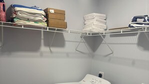 A laundry room with two front-loading washing machines, a drying rack, and shelves with folded towels and boxes. - Spacious 5-Bedroom Home Near Atlanta Airport Area (Atlanta)