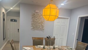 A dining room with a wooden table, six chairs, and a hanging light fixture. - Spacious 5-Bedroom Home Near Atlanta Airport Area (Atlanta)