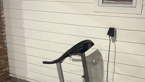 A treadmill in a covered outdoor area with a brick wall and a window. - Spacious 5-Bedroom Home Near Atlanta Airport Area (Atlanta)