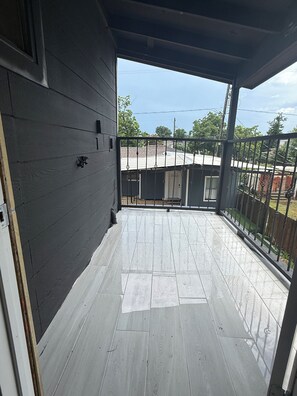 A covered balcony with a view of a residential area, a door, and a small shed. - Gorgeous 3-bedroom apartment with Balcony in vibrant Houston (Houston)