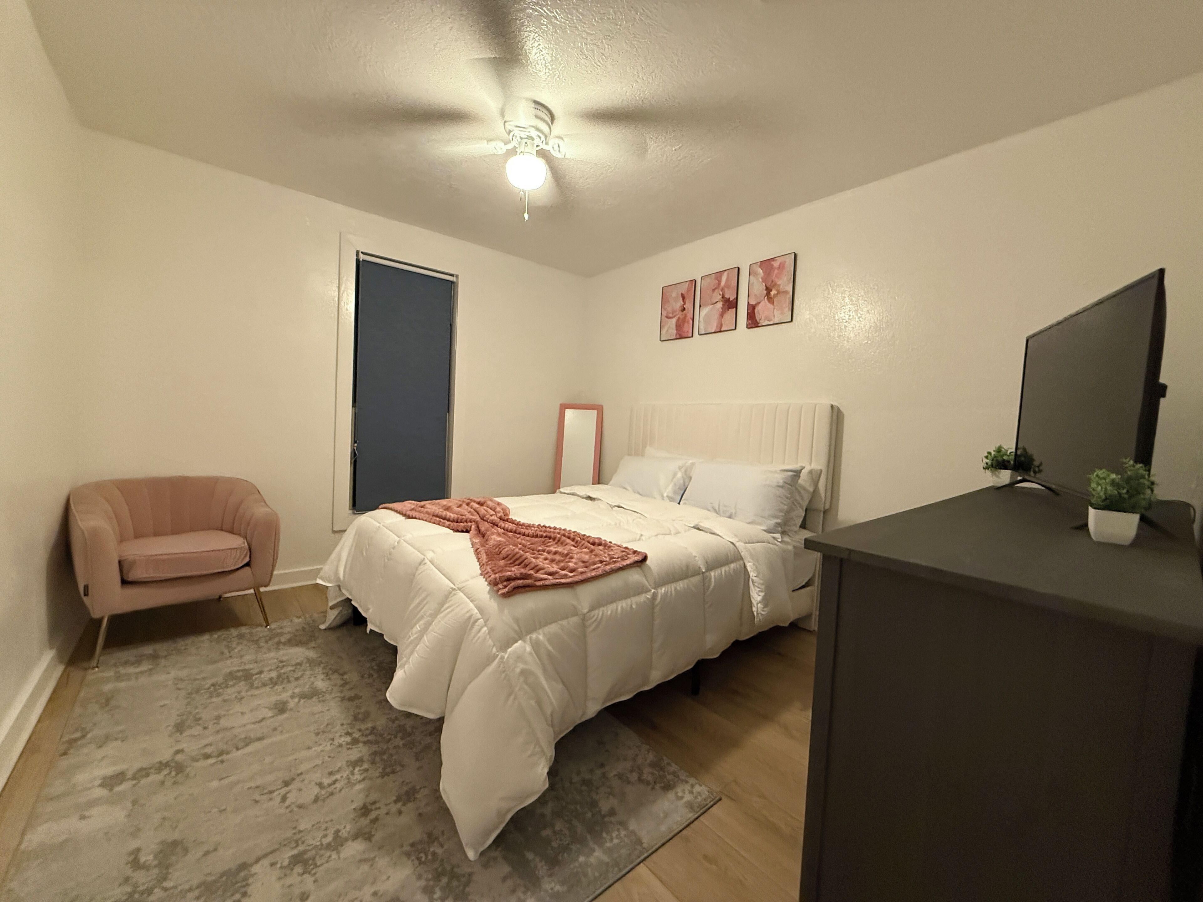 Un dormitorio con cama, una silla, un escritorio y un ventilador de techo.