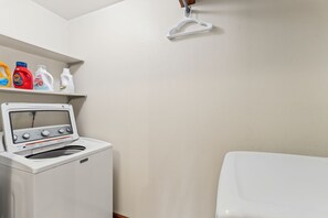 A laundry room with a washing machine, a dryer, and a shelf with detergent bottles. - Red Bird Retreat | Arctic Hot Tub | Stunning Views (Silverthorne)