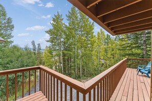 A wooden deck with a railing overlooking a forested area.