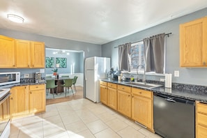 A modern kitchen with wooden cabinets, a black countertop, and a Bosch dishwasher. - Family-Friendly Provo Home w/ Parking (Provo)