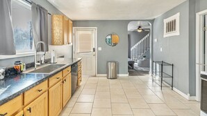 A kitchen with wooden cabinets, a stainless steel sink, and a window with curtains.