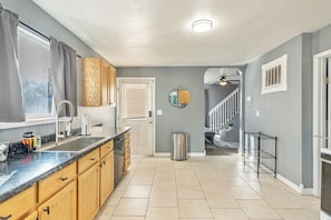 A kitchen with wooden cabinets, a stainless steel sink, and a window with curtains.